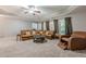 Spacious living room with a large leather sectional, tray ceiling, and ample natural light at 4891 Tarry Post Ln, Suwanee, GA 30024