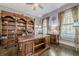 Elegant office features a custom wood desk and built-in shelving with views from the windows at 4891 Tarry Post Ln, Suwanee, GA 30024
