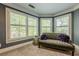 Cozy sitting area with large windows, tufted settee and decorative pillows at 4891 Tarry Post Ln, Suwanee, GA 30024