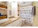 Bright bathroom with granite countertops, a white vanity, and a shower with bird patterned curtain at 5020 Huntshire Sw Ln, Lilburn, GA 30047