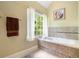 Relaxing bathroom featuring a soaking tub, large window with wooded view and decorative tile work at 5020 Huntshire Sw Ln, Lilburn, GA 30047