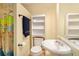 Well-lit bathroom with a white vanity, built-in shelves, and a shower with a decorative curtain at 5020 Huntshire Sw Ln, Lilburn, GA 30047