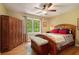 Comfortable bedroom featuring a ceiling fan, hardwood floors, and a large wardrobe at 5020 Huntshire Sw Ln, Lilburn, GA 30047