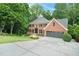 Gorgeous brick home with lush green landscaping, mature trees, and a long driveway leading to the attached garage at 5020 Huntshire Sw Ln, Lilburn, GA 30047