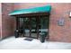 Inviting entrance to the building features a glass door, green awning, potted plants, and red brick at 115 W Peachtree Nw Pl # 709, Atlanta, GA 30313