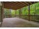 Inviting covered deck, featuring wood flooring and railing, offering a serene view of the lush greenery at 4555 Peachtree Dunwoody Rd, Sandy Springs, GA 30342