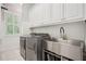 Well-lit laundry room featuring white cabinets, stainless steel appliances, and a convenient utility sink at 4555 Peachtree Dunwoody Rd, Sandy Springs, GA 30342