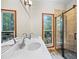 Bright bathroom with double sinks, a walk-in glass shower, wood floors, and lovely backyard views at 4805 Forest Way Ct, Marietta, GA 30066