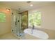 Bright bathroom featuring a glass shower, modern tub, and a large window offering natural light at 731 Sacketts Ct, Lawrenceville, GA 30043