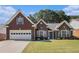 Charming brick home featuring a two-car garage, well-manicured lawn, and classic architectural details at 1180 Chandler Ridge Dr, Lawrenceville, GA 30045