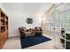 Cozy living room with large windows, comfortable seating, a bookshelf, and a dark blue rug at 1180 Chandler Ridge Dr, Lawrenceville, GA 30045