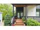 Stylish front porch with wood decking, black railing, modern door and lush landscaping at 1676 Carroll Nw Dr, Atlanta, GA 30318