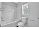 Full bathroom features a shower-tub combo and modern toilet under a bright window at 110 Village Green Cir, Tyrone, GA 30290