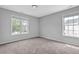A serene bedroom with neutral walls, plush carpeting, and two windows offering ample natural light at 110 Village Green Cir, Tyrone, GA 30290