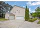 Side view of home with attached garage and large driveway and landscaped yard at 110 Village Green Cir, Tyrone, GA 30290