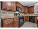 Close-up of kitchen showcasing wooden cabinets, tile backsplash, granite countertops, and modern black appliances at 110 Village Green Cir, Tyrone, GA 30290