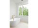 Bright bathroom featuring a white standalone tub with gold fixtures and large picture window with wooded view at 11548 Serenbe Ln, Chattahoochee Hills, GA 30268