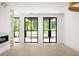 Bright living room with large black framed glass doors, hardwood floors, a modern fireplace, and built-in shelving at 11548 Serenbe Ln, Chattahoochee Hills, GA 30268