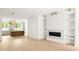Open-concept living room with hardwood floors, a modern fireplace, built-in shelving, and a view of the kitchen island at 11548 Serenbe Ln, Chattahoochee Hills, GA 30268