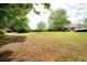 Expansive backyard with a lush lawn, mature trees, and a home in the distance at 1510 Pecan Plantation Ct, Loganville, GA 30052