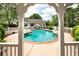 View of the sparkling backyard pool and home from under a charming white pergola at 1510 Pecan Plantation Ct, Loganville, GA 30052