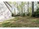 Side yard view featuring the exterior of the house, lush greenery, and mature trees at 4344 White Surrey Nw Dr, Kennesaw, GA 30144