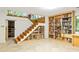 Basement staircase with shelving underneath, alongside a large bookshelf filled with books and tile flooring at 922 Barton Woods Ne Rd, Atlanta, GA 30307