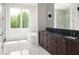 Bright bathroom with marble floors, soaking tub, large window, and double vanity with modern fixtures at 11554 Serenbe Ln, Chattahoochee Hills, GA 30268