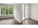 Bright bedroom featuring hardwood floors, white trim, and sliding doors leading to an outdoor balcony with wooded views at 11554 Serenbe Ln, Chattahoochee Hills, GA 30268
