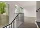 Modern hallway featuring sleek railings, wood floors, and expansive windows with views of the outdoors at 11554 Serenbe Ln, Chattahoochee Hills, GA 30268