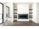 Bright living room with a modern fireplace and custom built-in shelving at 11554 Serenbe Ln, Chattahoochee Hills, GA 30268