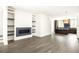 Open-concept living room with fireplace, built-in shelves and view of kitchen at 11554 Serenbe Ln, Chattahoochee Hills, GA 30268