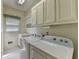 Functional laundry room with a sink, white cabinets, a blind-covered window, and modern washer and dryer units at 3003 Heavenly Ln, Snellville, GA 30078