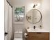 Bright bathroom with wood vanity, black trim on the round mirror, and a combo shower-tub at 310 Tradea Tarn, Roswell, GA 30076