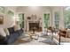 Cozy living room with a fireplace, light hardwood floors, modern furniture, and three large windows providing natural light at 310 Tradea Tarn, Roswell, GA 30076