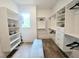 Spacious walk-in closet with custom shelving, drawers, bench, and wood flooring at 12520 Celestine Way, Milton, GA 30075