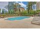 Outdoor pool with lounge chairs and city views beyond trees at 3445 Stratford Ne Rd # 305, Atlanta, GA 30326