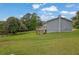 View of the home's backyard featuring a small deck, grassy yard, and lush foliage against a bright, cloudy sky at 4665 Big Valley Rd, Stone Mountain, GA 30083