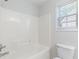 Bathroom featuring a tiled shower and tub combination with white toilet and window at 4353 Pond Edge Rd, Snellville, GA 30039