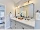 Bright bathroom with double sink vanity, stone countertop, framed mirror, and modern fixtures at 5702 Brynwood Nw Cir, Acworth, GA 30101