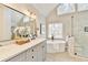 Bright bathroom featuring a soaking tub under windows, a glass shower, and double sink vanity at 5702 Brynwood Nw Cir, Acworth, GA 30101