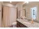 Bright bathroom featuring granite countertop, neutral walls, and a shower with a patterned curtain at 7045 Parrish Way, Cumming, GA 30040