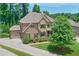 A beautiful house showcasing a manicured front yard, colorful landscaping, and a mix of brick and stone accents at 7045 Parrish Way, Cumming, GA 30040
