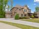 Elegant home showcasing brick and stone details, a three-car garage, and a manicured front lawn at 7045 Parrish Way, Cumming, GA 30040