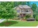 Beautiful home featuring a stone and brick exterior with lush landscaping and a well-maintained front lawn at 7045 Parrish Way, Cumming, GA 30040