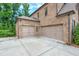 Two-car garage with a concrete parking pad complementing the home's brick exterior at 7045 Parrish Way, Cumming, GA 30040