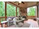 Relaxing covered porch with a stone fireplace, comfortable seating, and string lights at 7045 Parrish Way, Cumming, GA 30040