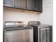 Well-equipped laundry room with modern, stainless steel washer and dryer units and storage cabinets at 2119 Dee Dee Muse Nw Ln, Atlanta, GA 30318