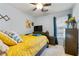 Cozy bedroom with a ceiling fan, a dark dresser, a colorful painting and a large window at 129 Lakepointe Ct, Stockbridge, GA 30281