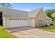 View of the home's side, showing the two-car garage and driveway on a sunny day at 129 Lakepointe Ct, Stockbridge, GA 30281